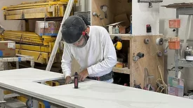 Worker wearing protective gear when finishing a sink cutout.