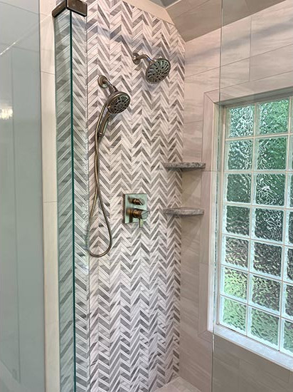 A Thassos marble mosaic in a chevron pattern was employed on the wet wall to accent the stone-inspired porcelain tile on the adjacent walls and floors.