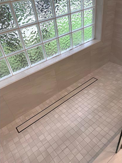 The linear drain from the original bathroom as kept intact and complemented with 2- x 2-inch, porcelain mosaic tiles from Happy Floors in Miami, FL.