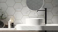 Modern bathroom with white hexagonal marble tiles, gold grout, white sink, and black faucet