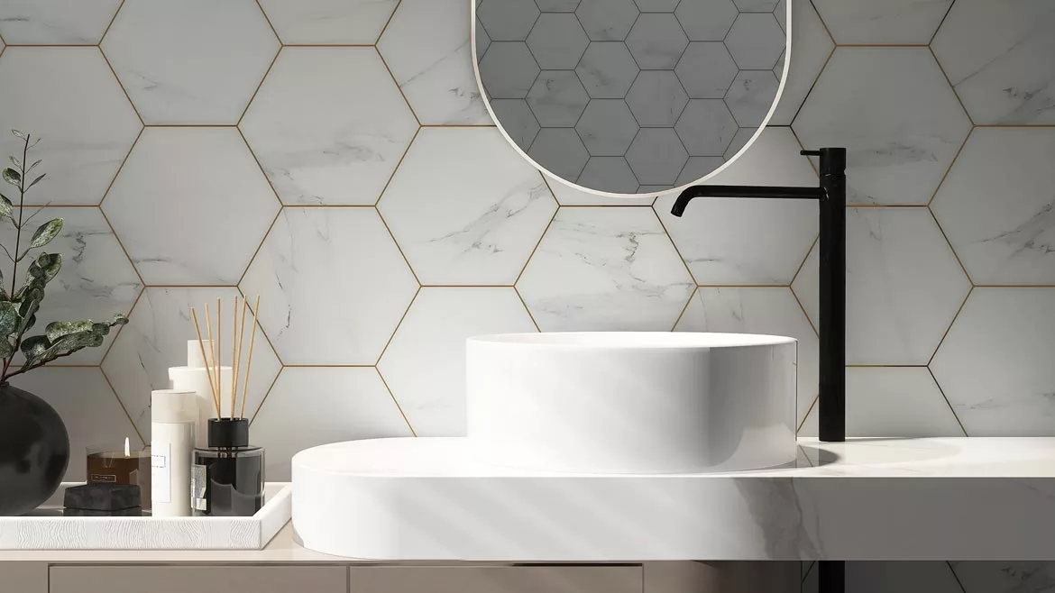 Modern bathroom with white hexagonal marble tiles, gold grout, white sink, and black faucet